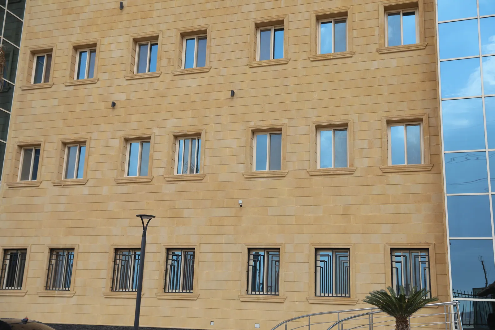 Finished administrative building with stone facade, sliding-window rows, and a glazed corner